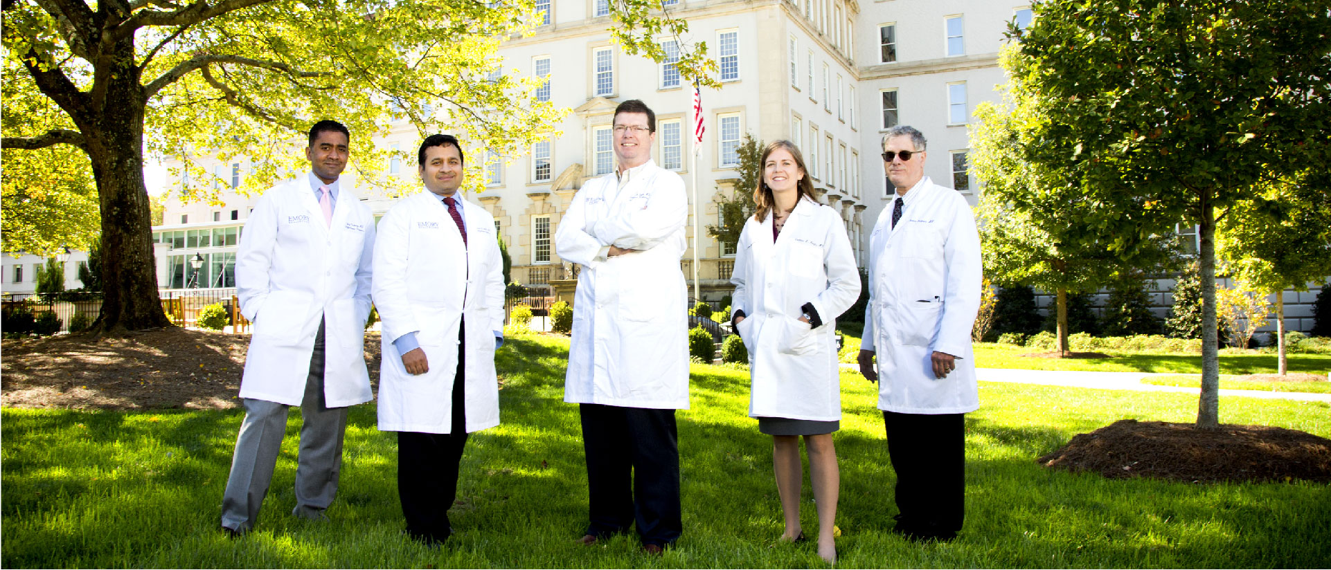Group of doctors standing on grass in front of building